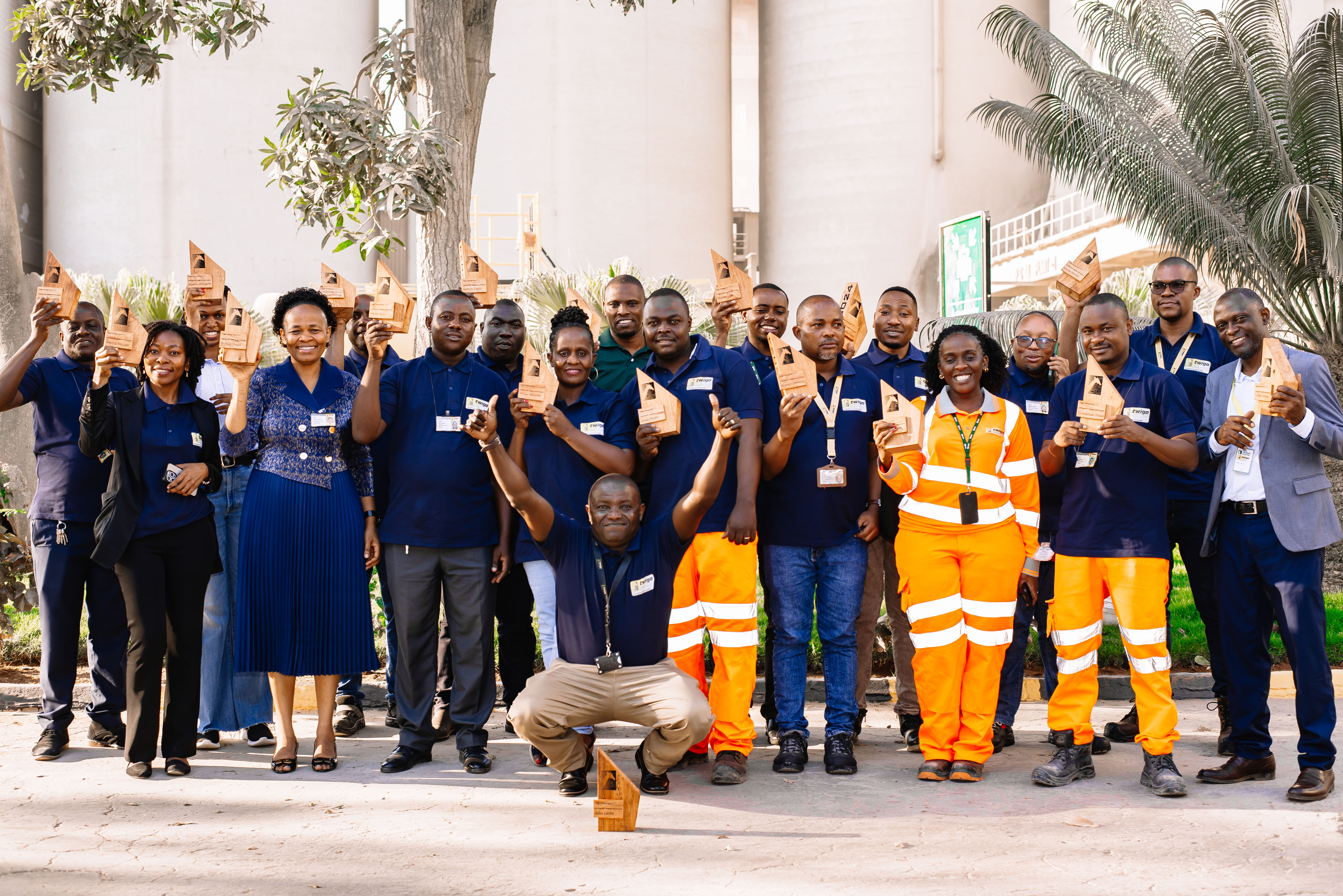 A group of Heidelberg Materials employees, some wearing uniforms, holding awards and posing outside a building.